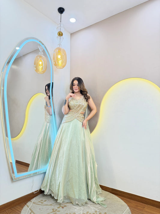 Mint green party wear lehenga with shimmer fabric and golden criss cross blouse side pose