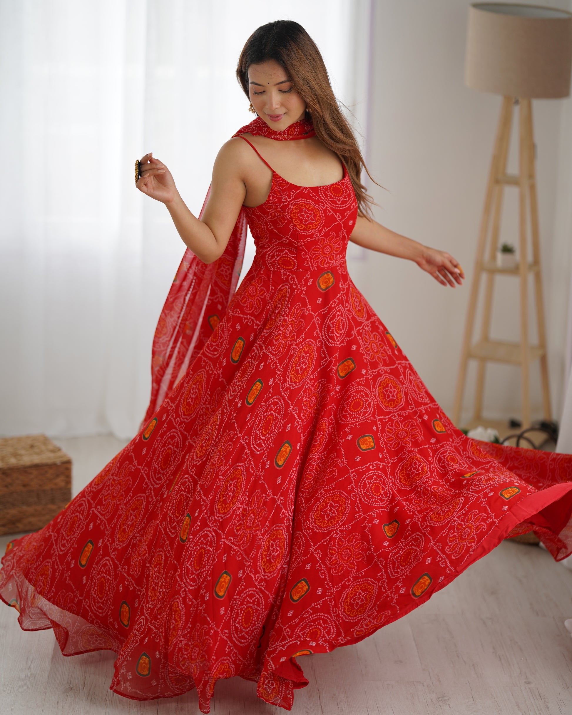 Woman wearing a red dress with floral patterns in a bright room.