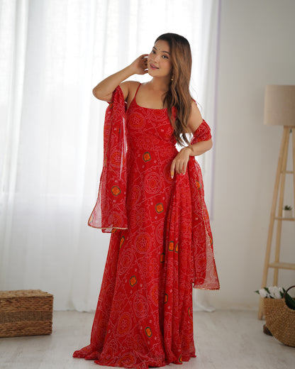 Woman wearing a red patterned dress with a matching dupatta in a minimalistic room.