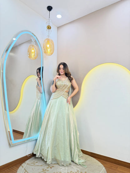Mint green party wear lehenga with shimmer fabric and golden criss cross blouse side pose