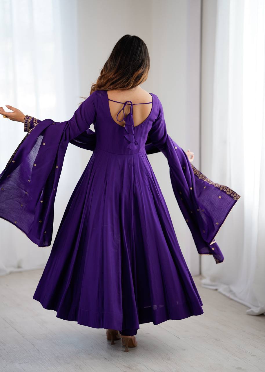 Woman wearing a purple dress with bell sleeves in a room with white curtains.