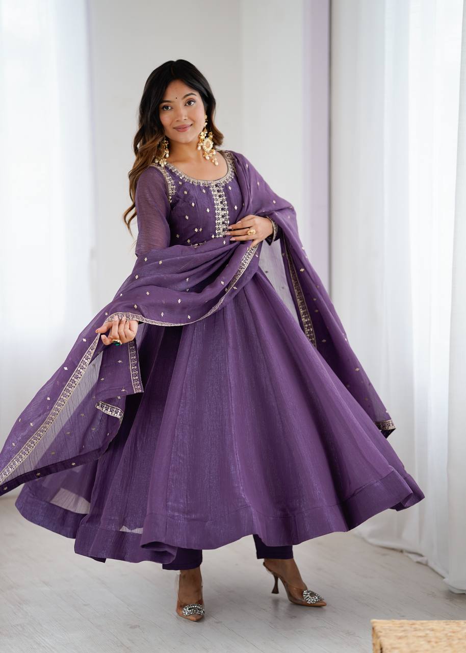 Woman wearing a purple traditional outfit with gold details in a bright room.